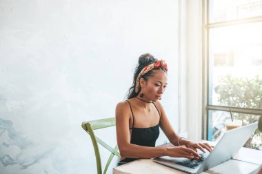 Kafede dizüstü bilgisayarı ve kahvesiyle çalışan Asyalı kadın