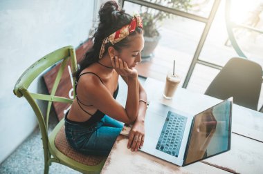 Kafede dizüstü bilgisayarı ve kahvesiyle çalışan Asyalı kadın