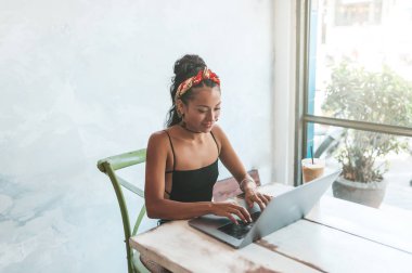 Kafede dizüstü bilgisayarı ve kahvesiyle çalışan Asyalı kadın