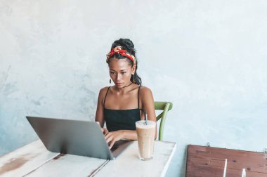 Kafede dizüstü bilgisayarı ve kahvesiyle çalışan Asyalı kadın