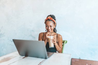 Kafede dizüstü bilgisayarı ve kahvesiyle çalışan Asyalı kadın