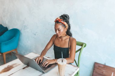 Kafede dizüstü bilgisayarı ve kahvesiyle çalışan Asyalı kadın