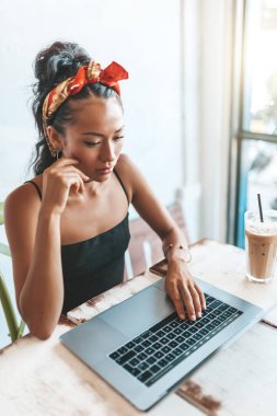 Kafede dizüstü bilgisayarı ve kahvesiyle çalışan Asyalı kadın