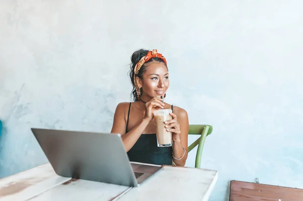 Азиатка, работающая с ноутбуком и кофе в кафе — стоковое фото