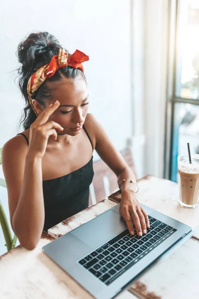 Kafede dizüstü bilgisayarı ve kahvesiyle çalışan Asyalı kadın