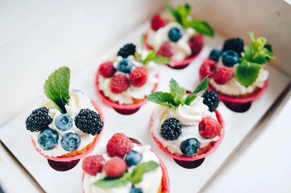 Cupcakes decorados con crema, bayas y miny en caja . — Foto de Stock