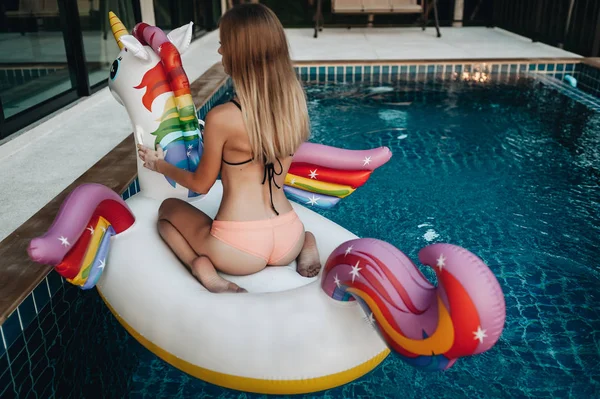 Sexy Frau entspannt auf dem Einhorn in einem Swimmingpool — Stockfoto