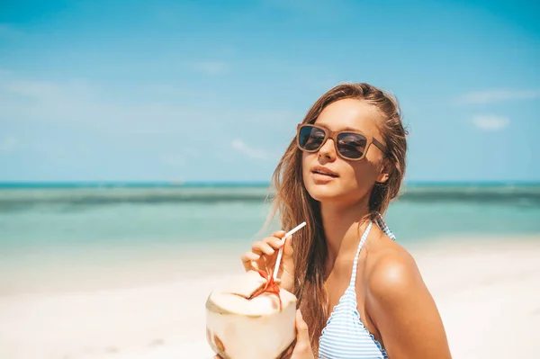 Ung vacker kvinna dricker kokos vatten på tropiska stranden — Stockfoto