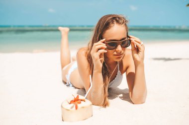 Tropikal plajda hindistan cevizi suyu içen genç güzel kadın