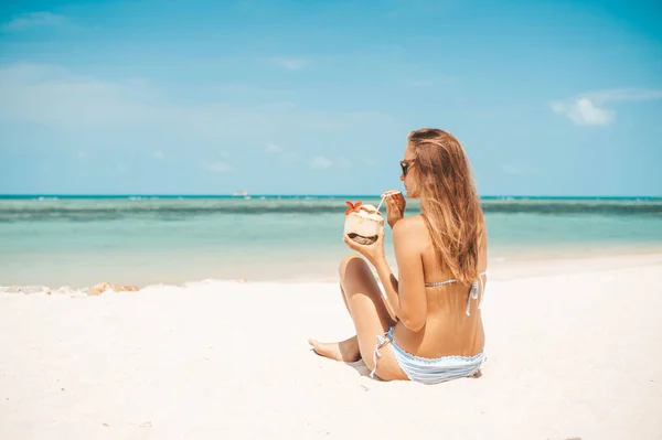 熱帯のビーチでココナッツウォーターを飲む若い美しい女性 — ストック写真