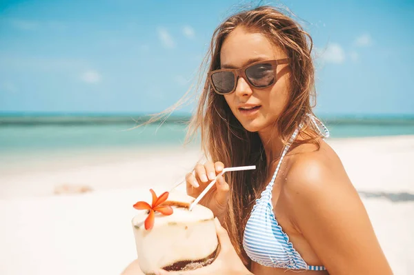 Ung vacker kvinna dricker kokos vatten på tropiska stranden — Stockfoto