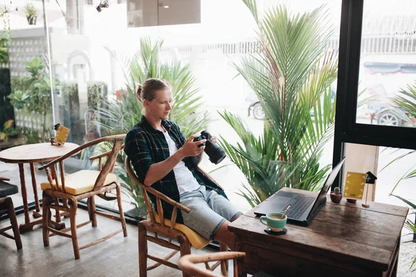 Kreativer Fotograf mit professioneller Kamera im Café mit Laptop. — Stockfoto