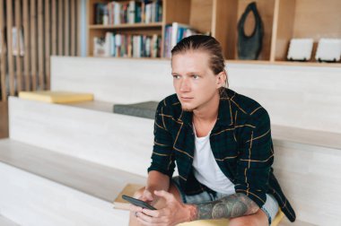 Akıllı telefon ile otelde oturan yakışıklı adam, internet tarama