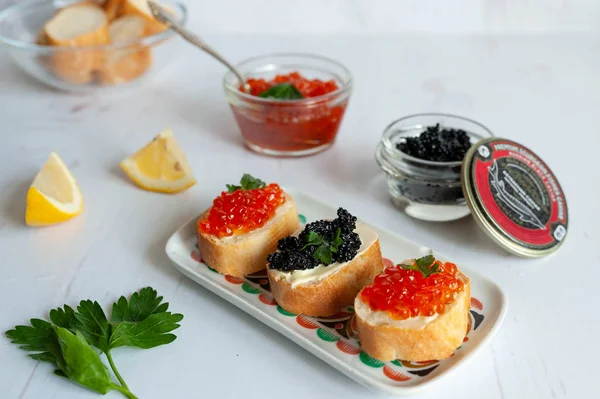 Sanduíches com caviar de salmão vermelho e caviar preto de esturjão no fundo branco — Fotografia de Stock