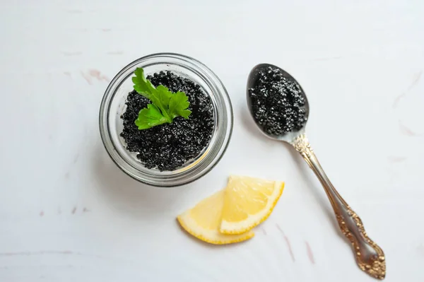 Tarro de caviar de esturión negro y cuchara con caviar sobre el fondo blanco — Foto de Stock