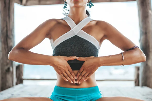 Genç kadın plajda ahşap çardak yoga yapıyor