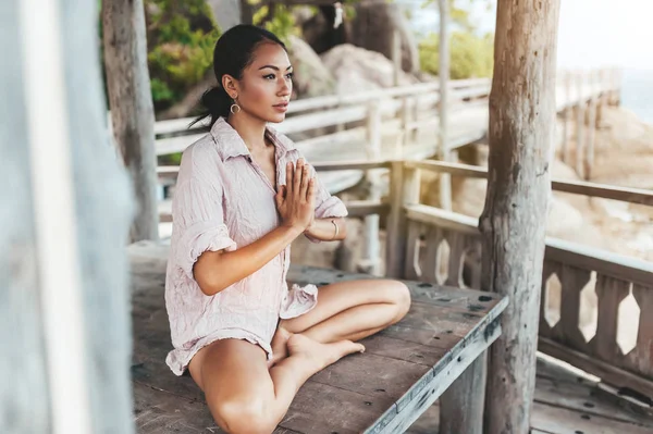 Giovane donna che medita in una posa yoga in spiaggia — Foto Stock