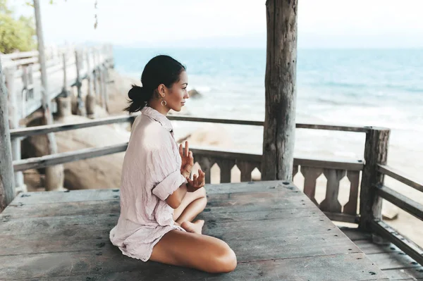 Giovane donna che medita in una posa yoga in spiaggia — Foto Stock