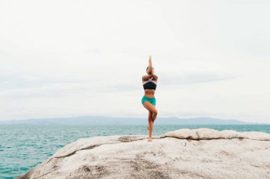 Genç kadın taşlar üzerinde yoga yapıyor