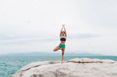 Genç kadın taşlar üzerinde yoga yapıyor