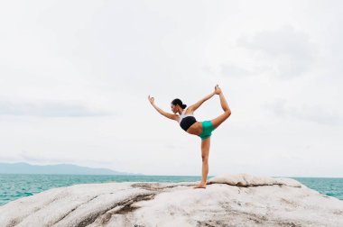Genç kadın taşlar üzerinde yoga yapıyor