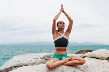 Genç kadın taşlar üzerinde yoga yapıyor