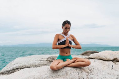 Genç kadın taşlar üzerinde yoga yapıyor