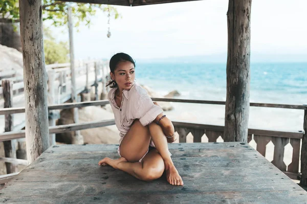 Wanita muda melakukan yoga di gazebo kayu di pantai — Stok Foto