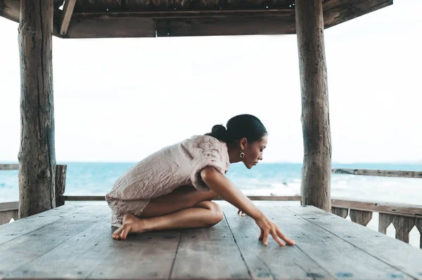 Młoda kobieta robi jogę w drewnianej altanie na plaży — Zdjęcie stockowe