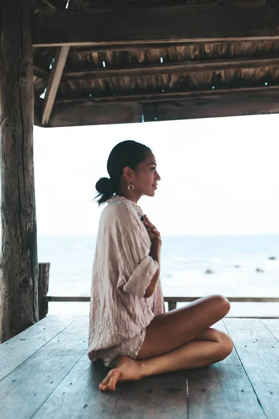 Młoda kobieta robi jogę w drewnianej altanie na plaży — Zdjęcie stockowe