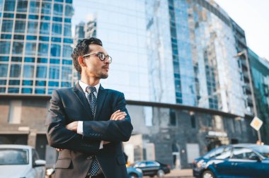 Arka planda şehir manzarası ile açık havada duran tam takım elbiseli modern işadamı