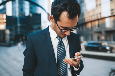 Arka planda şehir manzarası ile açık havada duran tam takım elbiseli modern işadamı