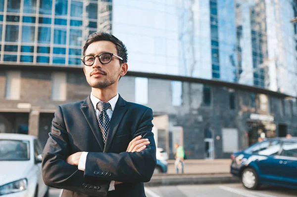 Hombre de negocios moderno en traje completo de pie al aire libre con paisaje urbano en el fondo — Foto de Stock