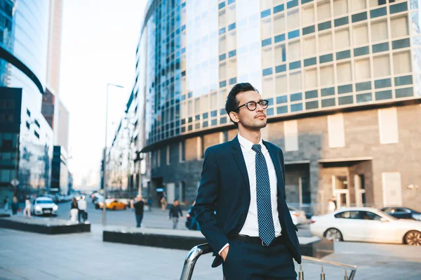 Hombre de negocios moderno en traje completo de pie al aire libre con paisaje urbano en el fondo — Foto de Stock