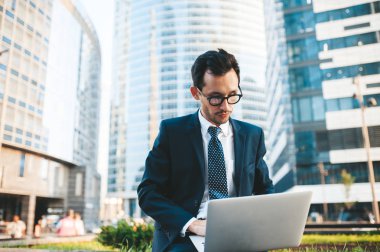 Arka planda şehir manzarası ile açık havada duran tam takım elbiseli modern işadamı