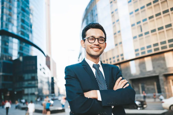 Modern businessman in full suit standing outdoors with cityscape in the background