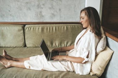 Kanepede bilgisayar başında çalışan bir kadın. Boşluğu kopyala