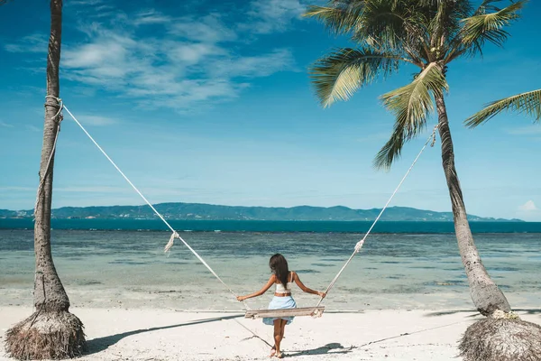 青いスカートの女性と白いトップスイングで熱帯のビーチでタイ — ストック写真