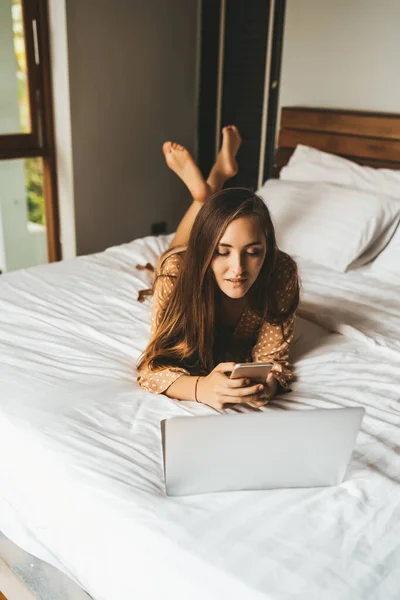 Жінка Волоссям Лежить Ліжку Ноутбуком Балакає Телефону Спальні — стокове фото