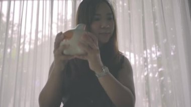 Kadın domuz kumbarasına bozuk para sokuyor.