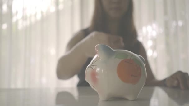 Vrouw Voegt Een Munt Een Spaarvarken Bank — Stockvideo