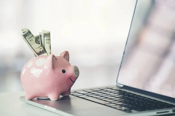 Piggy bank with laptop on the desk — Stock Photo, Image