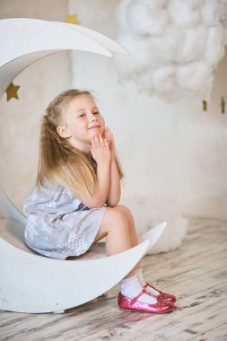 rüya gibi bir ahşap dekoratif ay bulutların ve yıldızların üzerinde oturan kız. çocukluk kavramı. peri masallarına inanç