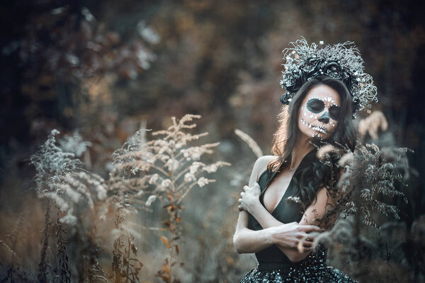 Closeup portrait of Calavera Catrina in black dress. Sugar skull makeup. Dia de los muertos. Day of The Dead. Halloween in wood. Outside