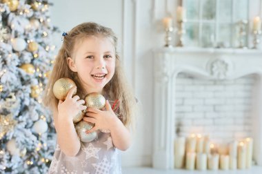 Kız evde topları ile Noel ağacı süsleme. kış tatil ve insanlar kavramı. Mutlu Noeller ve mutlu tatiller