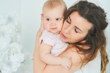 Güzel genç Anne kucağında bebek kızla. Mutlu bir aile, annelik kavramı. Yatak odasında bebeği ile oynarken annesi.