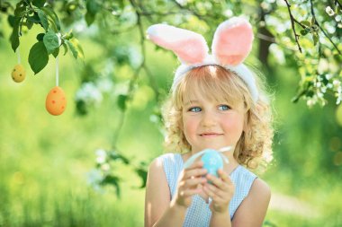 Paskalya yumurtaları ve tavşan kulakları Garden ile şirin komik kız. Paskalya kavramı. Paskalya yumurtası avı gülen çocuk. Çocuk Parkı yumurta, bahar kavramı ile