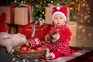 Noel ağacının altında küçük kız. şömine ile domuz oyuncak, Noel ağacının altında hediyelerle Noel Baba şapkalı kız bebek