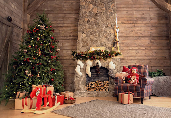 The little girl under the Christmas tree. baby girl in Santa Claus hat with gifts under Christmas tree at fireplace with piggy toy