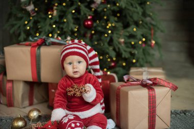 Noel ağacının altında küçük kız. Şömine, Noel ağacının altında hediyelerle Noel Baba şapkalı kız bebek. kopya alanı